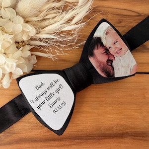 May include: Black bow tie with a personalized photo of a man and child. The bow tie has a white section with the text "Dad, I always will be your little girl! Laurie 03.15.29".