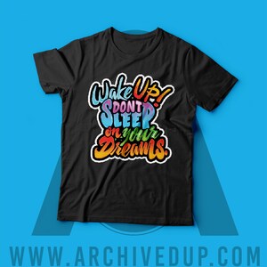 Może przedstawiać: Czarny T-shirt z kolorową grafiką, na kt&oacute;rej widnieje napis "Wake Up! Don't Sleep on Your Dreams."