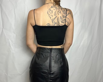 Può includere: Gonna corta in pelle nera con cerniera sul retro.