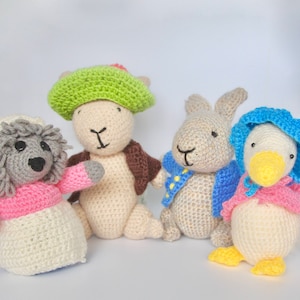 May include: Four crocheted stuffed animals: a grey sheep with a pink dress, a green-hatted bunny with a brown jacket, a grey rabbit with a blue jacket, and a white duck with a pink dress and blue bonnet.