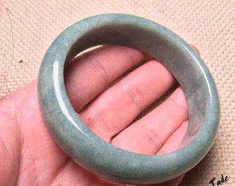 May include: A green jade bangle bracelet. The bracelet is smooth and polished, with a light green colour.