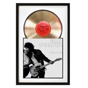 May include: Framed gold record and album cover of Bruce Springsteen's "Born to Run." The gold record is displayed above the album cover, both set against a white background within a black frame. The album cover features a black and white photo of Springsteen.