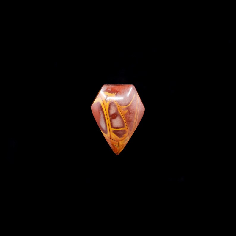 May include: A red, yellow, and white gemstone cabochon cut in a diamond shape.