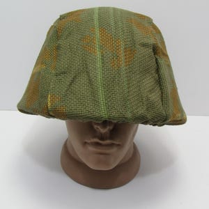 May include: A green and brown patterned hat with a brim, displayed on a mannequin head. The hat features a woven texture and a camouflage-like design. The color palette includes shades of green and brown.