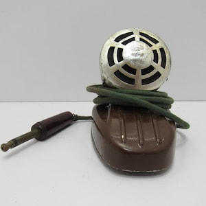 May include: Vintage microphone with a silver metal head and a brown base. The microphone has a dark green cord and a brown plug. The microphone is likely from the mid-20th century and is in good condition.