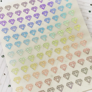 May include: A sheet of iridescent diamond stickers in a rainbow of colors. The stickers are arranged in a grid pattern on a white background.