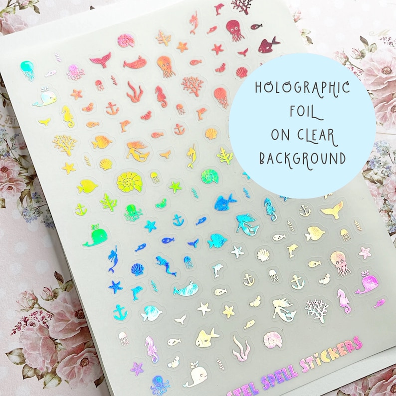 May include: Holographic foil stickers on a clear background, featuring various sea creatures and nautical elements. The stickers include fish, mermaids, anchors, and coral in a rainbow of colors. The text on the image says "Holographic Foil on Clear Background".