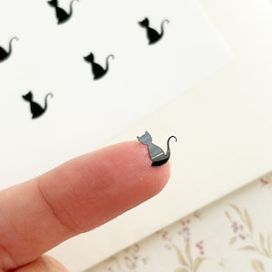 May include: A sheet of black cat stickers. The stickers are small and feature a simple silhouette of a cat sitting with its tail curled around its body.