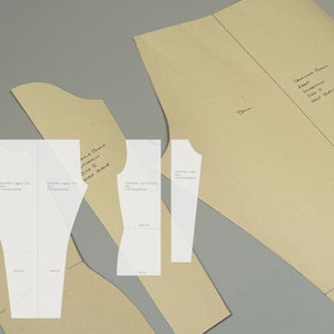 May include: Four pieces of brown paper with handwritten instructions for a sewing pattern. The pattern is for a "Stretch Tunic" in size "S" and includes instructions for a "Half Seam".