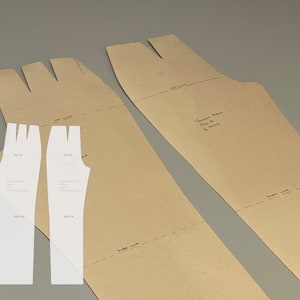 Peut inclure: Deux patrons de vêtement en papier blanc, avec des marques pour les lignes de couture et une ligne de hanche. Les patrons sont disposés sur un fond de papier brun avec des instructions manuscrites pour un "Dos de pantalon" taille 8, échelle 1/2.
