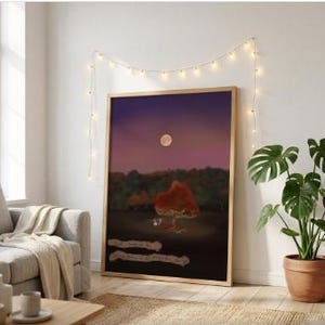 May include: A rectangular framed wall art print featuring a night landscape with a full moon, a dark forest, and a single orange tree. The bottom section contains two lines of text in a light-coloured, script-style font against a dark background.