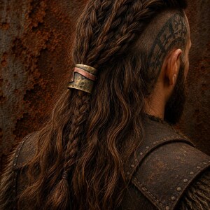 May include: A metallic hair cuff featuring a hammered brass finish with a contrasting copper-colored band. The cylindrical accessory secures a section of long, wavy brown hair that is styled with multiple braids and a shaved side section.