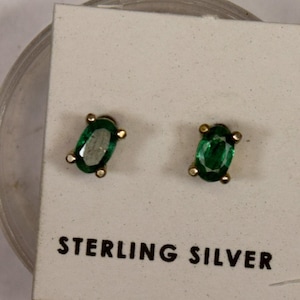 May include: A pair of sterling silver earrings with oval-shaped green gemstones.