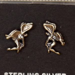 May include: A pair of sterling silver earrings featuring a fairy design. The earrings are displayed on a black card with the words "Sterling Silver" printed on it.