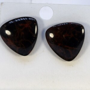 May include: A pair of triangular earrings with a dark brown and red marbled pattern.