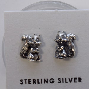May include: A pair of sterling silver earrings featuring a squirrel design. The earrings are displayed on a white card with the words "Sterling Silver" printed on it.