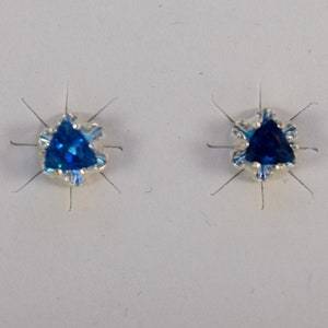 May include: A pair of silver stud earrings with blue triangular gemstones.