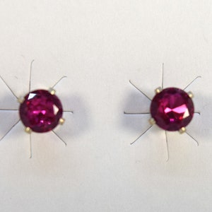 Pode incluir: Um par de brincos de pressão com pedras redondas de cor rosa escuro engastadas em prata.