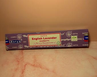 May include: Purple and white box of Satya English Lavender Agarbatti incense sticks. The box has the text "Satya English Lavender Agarbatti" and "Shrinivas "Sugandhalaya" LLP" printed on it.