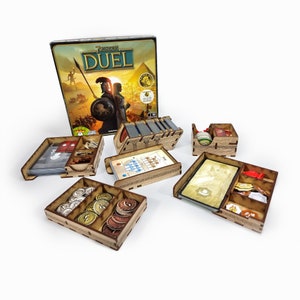 May include: Wooden organiser set for the board game 7 Wonders Duel. The set includes multiple compartments for storing cards, tokens, and other game components. The box for the game is also shown in the image.