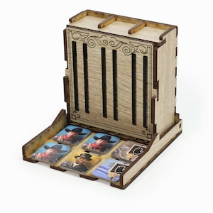 Può includere: Organizzatore in legno per un gioco da tavolo con slot per carte e un vassoio per gettoni. Il vassoio contiene sei gettoni con immagini di persone e una mano con una pistola. L'organizzatore è in legno marrone chiaro con accenti marrone scuro.