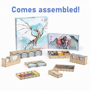 May include: A collection of board game components, including boxes and wooden organizers. The main box features a dragon illustration with the text "WYRMSPAN". Additional text reads "Comes assembled!"