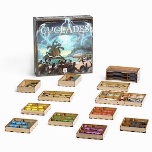 Puede incluir: Una caja de juego de mesa titulada "Cyclades" con una ilustración mitológica, acompañada de varias bandejas de almacenamiento de madera llenas de piezas de juego de varios colores. Las piezas del juego incluyen monedas, figuras y otros componentes.
