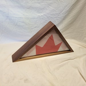 May include: A wooden triangular shadow box with a red maple leaf design inside. The shadow box is made of dark wood and has a glass front.