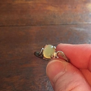 May include: A silver ring with a light green oval-shaped gemstone.