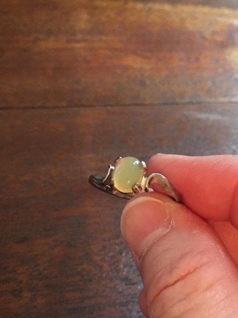 May include: A silver ring with a light green oval-shaped gemstone.