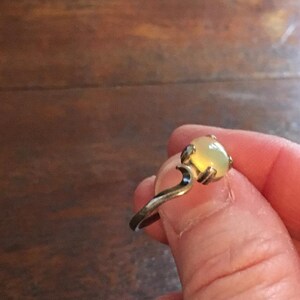 May include: A silver ring with a light yellow oval-shaped gemstone.