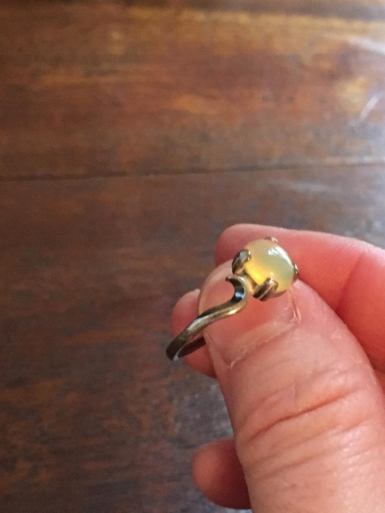 May include: A silver ring with a light yellow oval-shaped gemstone.