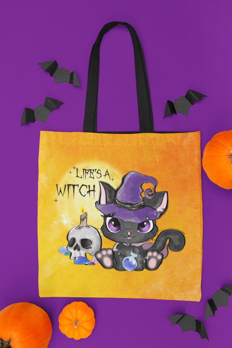 May include: A yellow canvas tote bag with black straps featuring a black cat wearing a purple witch hat and holding a potion bottle. The text "Life's a Witch" is printed on the bag.