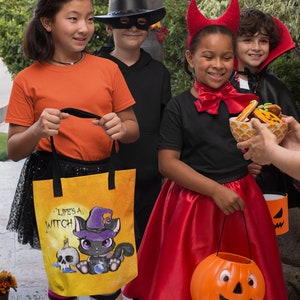 May include: Four children dressed in Halloween costumes, two girls and two boys, are trick-or-treating. One girl is wearing a red devil costume and holding a pumpkin-shaped bucket. Another girl is wearing an orange shirt and a black witch hat and carrying a yellow tote bag with a black cat illustration and the text "Life's a Witch". A boy is wearing a black cowboy hat and a black mask. Another boy is wearing a black cape and a vampire costume.