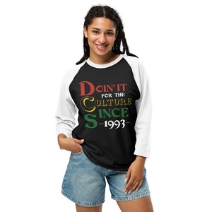 May include: Black and white baseball tee shirt with a red, yellow and green graphic that says "Doin' It For The Culture Since -1993-"