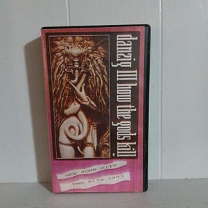 May include: A vintage VHS tape for the album "Danzig III: How the Gods Kill" with a pink and black cover. The cover art features a detailed illustration of a figure with a serpent. The text "New York City The Ritz 1993" is also visible.