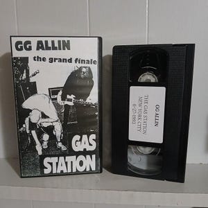 May include: A black VHS tape and case featuring the text "GG ALLIN the grand finale GAS STATION NEW YORK CITY 6-27-1993". The case has a black and white graphic of a band performing.