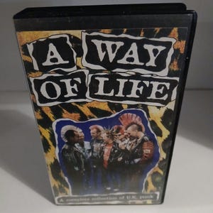 May include: A VHS tape with a black case and a colorful cover featuring the text "A Way Of Life" in black and white. The cover also features a group of people with mohawks and punk rock clothing.