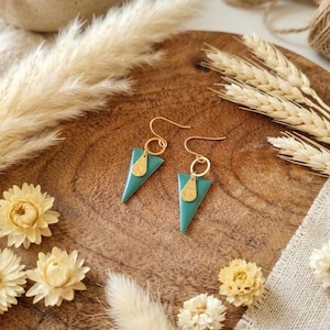May include: A pair of dangle earrings featuring a teal triangular pendant suspended from a gold-toned circular link and a small gold-toned teardrop-shaped charm. The earrings are attached to gold-toned ear wires for pierced ears.