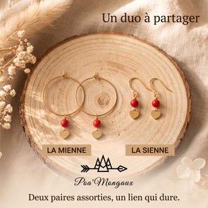 May include: Two pairs of gold-toned earrings featuring red spherical beads and small heart-shaped charms. One pair consists of hoop earrings, while the other features hook-style earrings. Text on the image reads: Un duo à partager, LA MIENNE, LA SIENNE, Poa'Mongaux, Deux paires assorties, un lien qui dure.