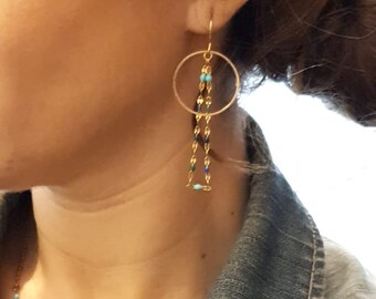 Gold-colored dangling earrings with brass hoops and blue monochrome chains. Jewelry for women. Handcrafted jewelry gift