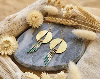 May include: A pair of gold-toned circular earrings featuring a brushed metal finish and a triangular cutout. Each earring is adorned with a fringe of small, multi-colored beads in shades of turquoise, white, and metallic bronze, suspended from a hook.