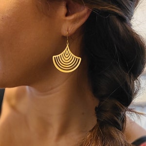 Peut inclure: Boucles d'oreilles en or avec un design géométrique en forme d'éventail. Les boucles d'oreilles sont en métal fin et ont un aspect délicat et moderne.