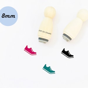 May include: A set of three wooden stamps with a running shoe design. The stamps are 8mm in diameter and are labeled "JUST GO STAMPS". The shoe designs are in red, black, and green.