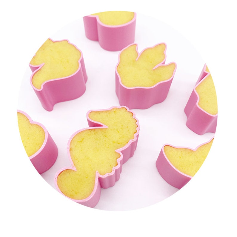 K&ouml;nnte beinhalten: Ein Set aus rosa Silikonformen in Form von Seepferdchen und einem Seestern. Die Formen sind mit einem gelben Teig gef&uuml;llt und bereit zum Backen.