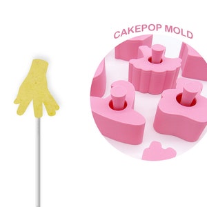 May include: Pink cake pop mold with a variety of shapes, including a ballerina, a heart, and a cloud. The mold is made of silicone and is designed to create cake pops that are easy to remove. CAKEPOP MOLD is written in white letters on a pink circle.