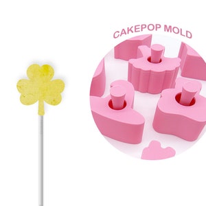 May include: Pink cake pop mold with a variety of shapes, including a ballerina, a heart, and a cloud. The mold is made of silicone and is designed to create cake pops that are easy to remove. The mold is labeled "Cakepop Mold".