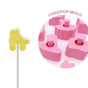 Könnte beinhalten: Rosa Cake-Pop-Form mit einem Rollschuh-Design. Die Form ist aus Silikon und hat eine Antihaftbeschichtung. Die Form ist so konzipiert, dass Cake Pops mit einem Durchmesser von etwa 5 cm entstehen. CAKEPOP MOLD ist in schwarzer Schrift auf weißem Hintergrund geschrieben.