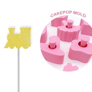 May include: Pink cake pop mold with a train design. The mold is made of silicone and has a non-stick surface. CAKEPOP MOLD is written on the image.