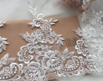 May include: White lace trim with a floral design. The lace has a delicate, intricate pattern with small pearls.